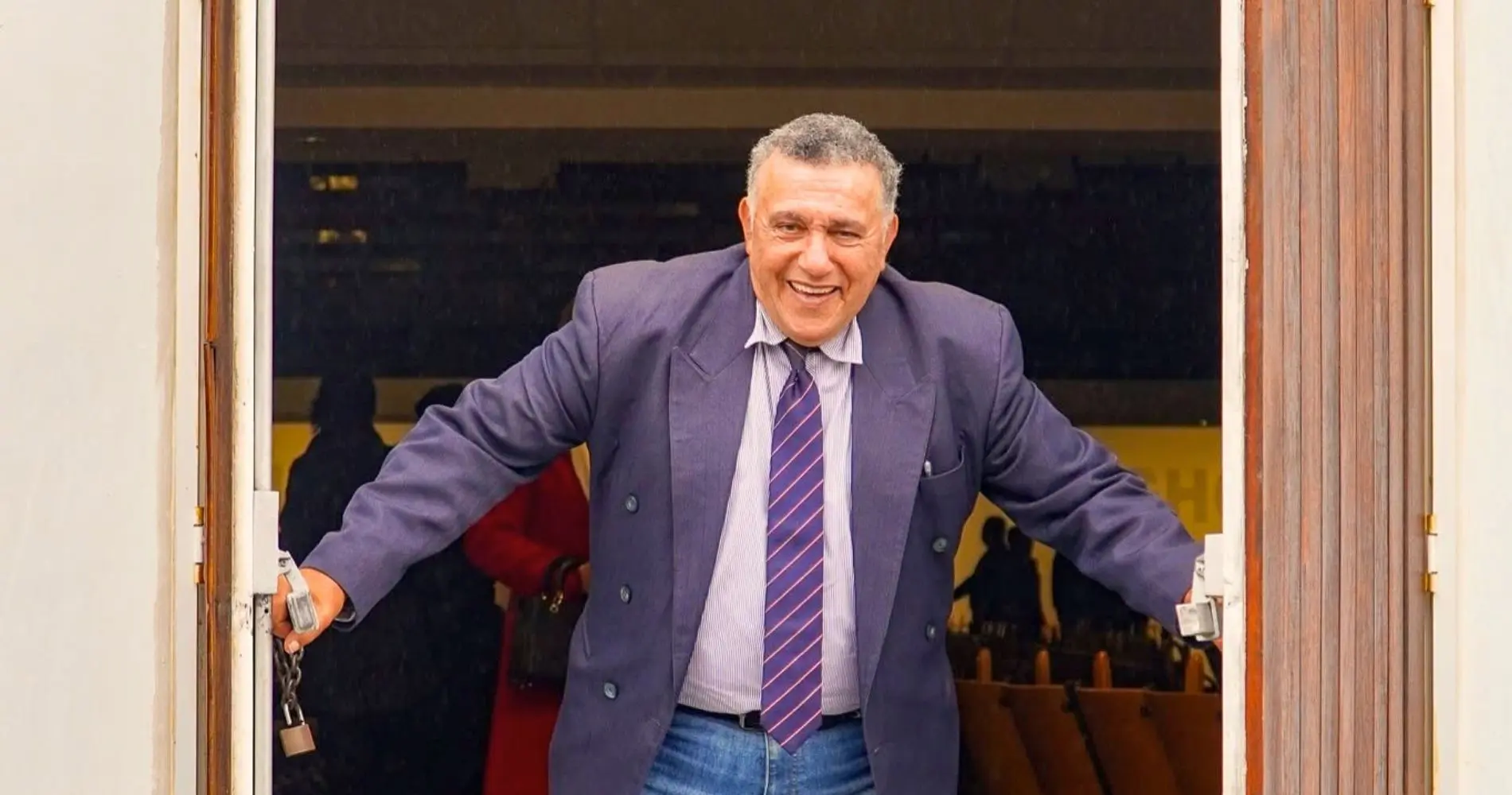 A man holding open the doors of a church, welcoming people in